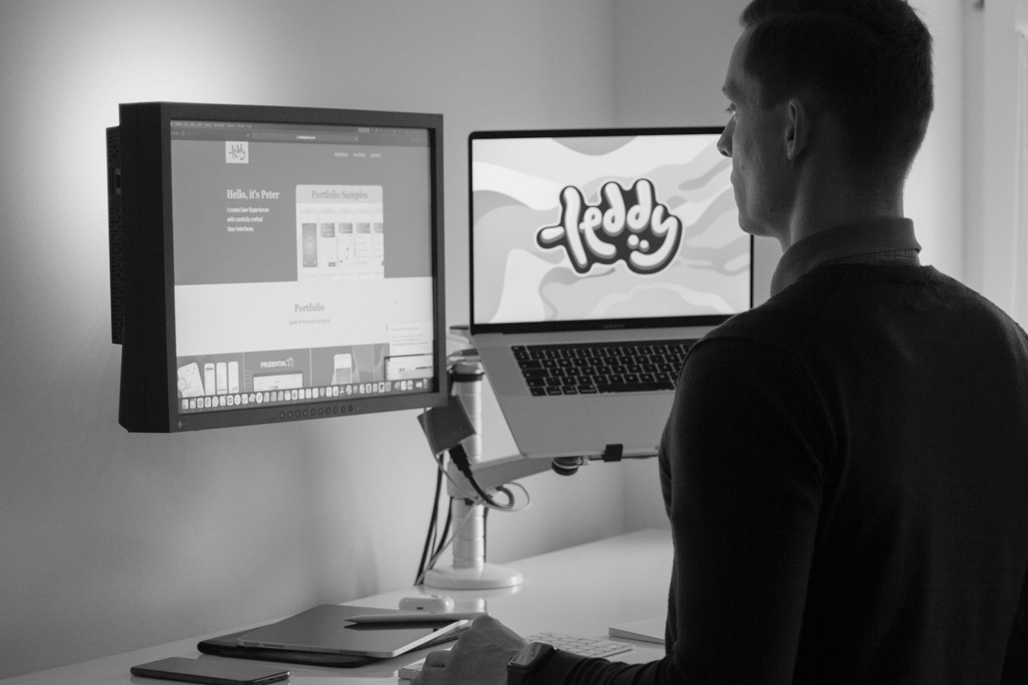 Man works at a modern desk with dual monitors.